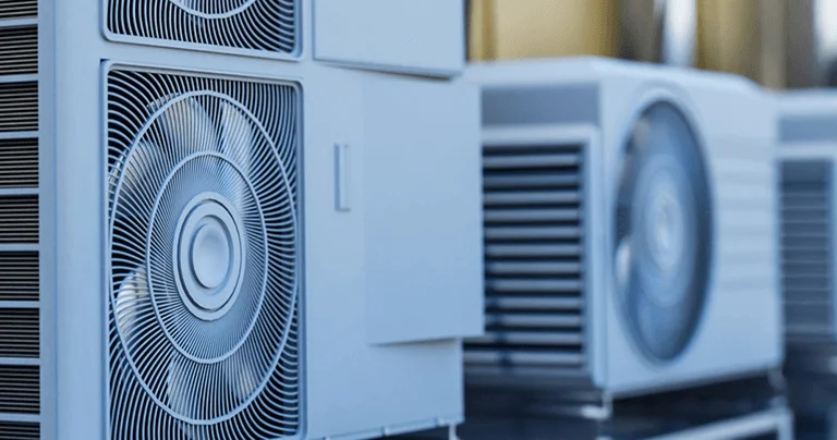 Row of modern air conditioning units against a blue background, featuring intricate metal grilles and circular fans.