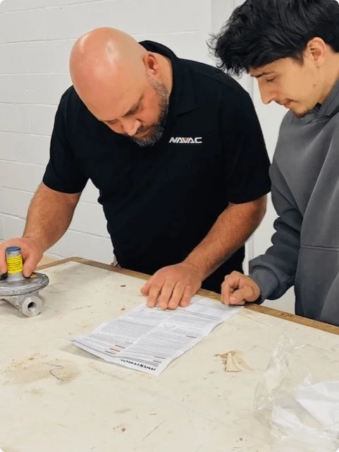 Two men are focused on a table, discussing and reviewing a document together.