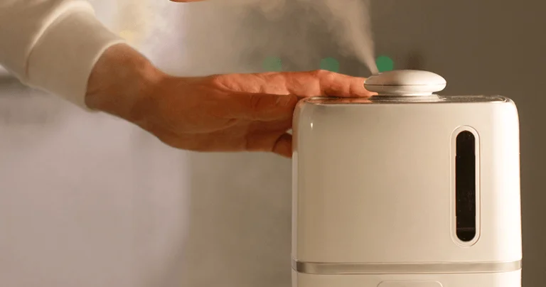 A person sprays a white liquid onto a white object, demonstrating a cleaning or coating process.