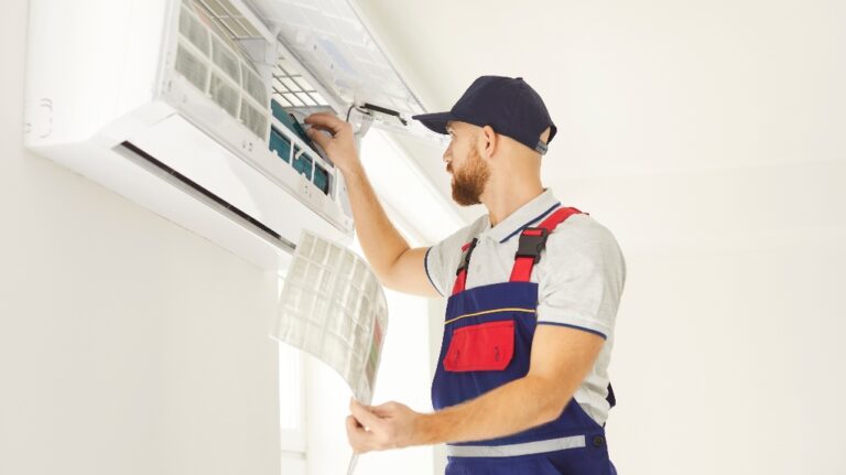 A worker cleans the filter in an air conditioner