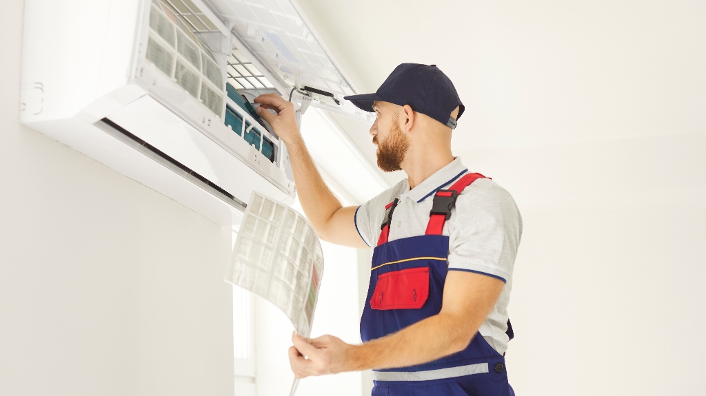 A worker cleans the filter in an air conditioner